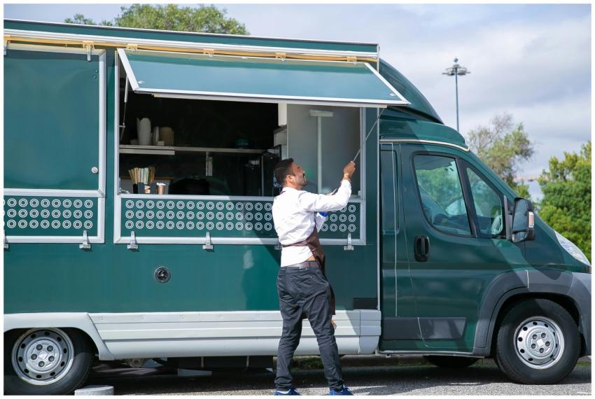 Side view young waiter in apron standing outside f