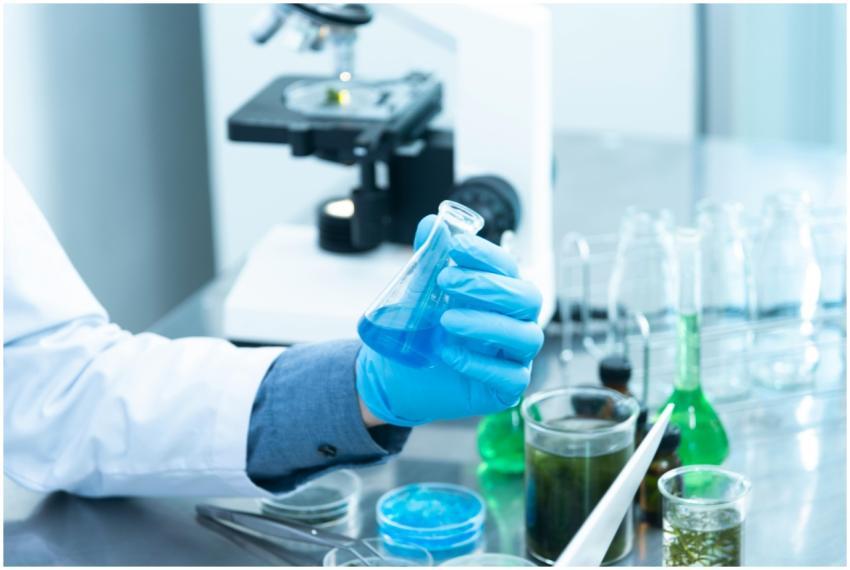 Scientist in gloves analyzing blue liquid in a lab