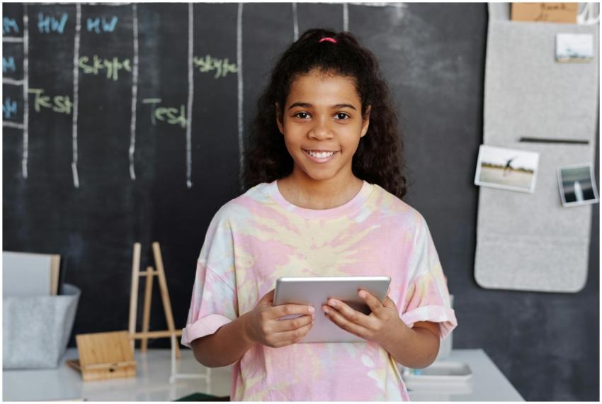 Cheerful girl holding a tablet in a modern classro
