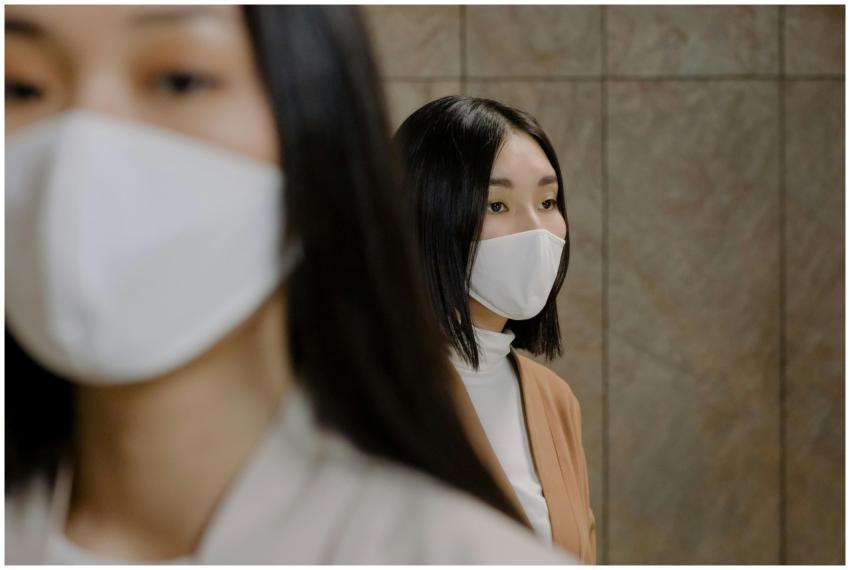 Two women wearing face masks indoors, emphasizing