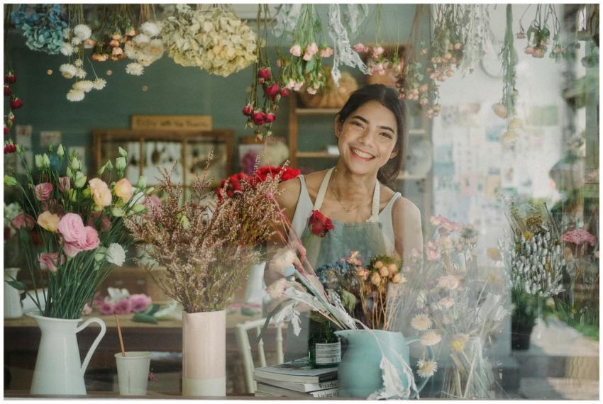 Cheerful female florist arranges colorful flowers