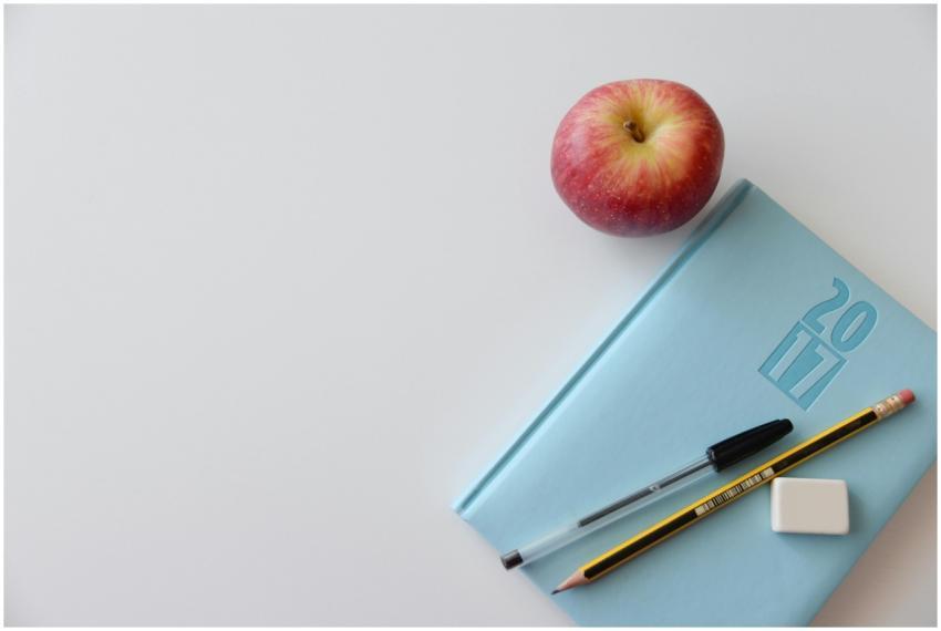 A minimalist flat lay of a study desk with a red a