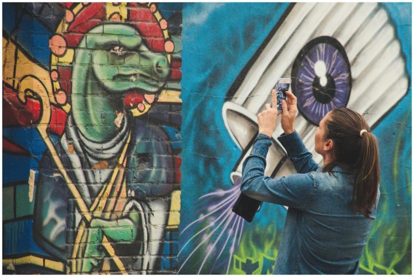 A woman photographs vibrant graffiti art on a city