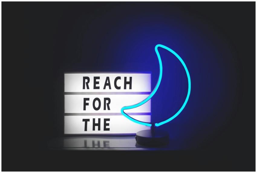 A neon crescent moon sign with a motivational quot