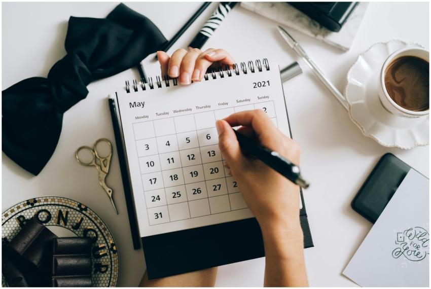 Top view of hands using a planner with coffee and