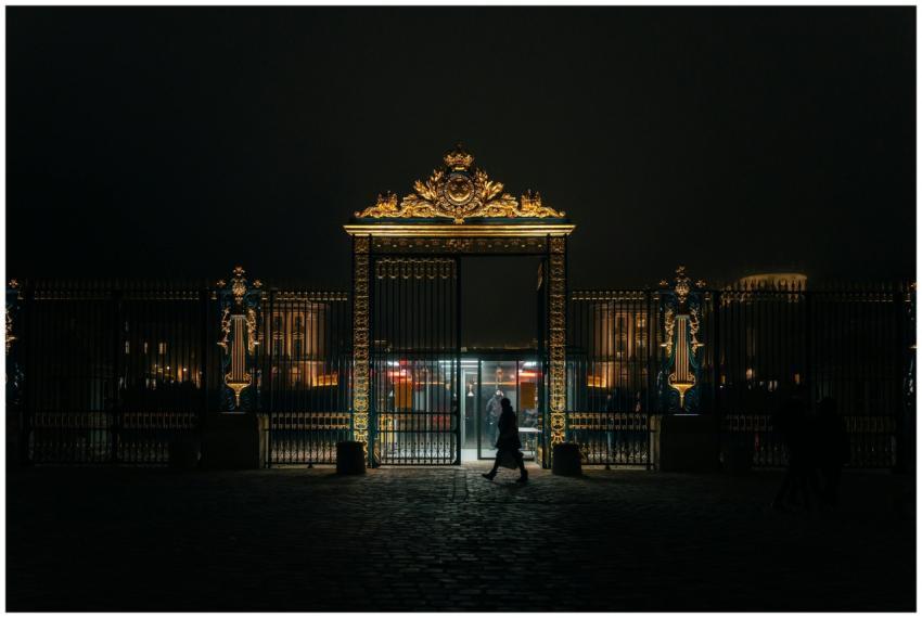 Night view of the ornate gates of Versailles Palac