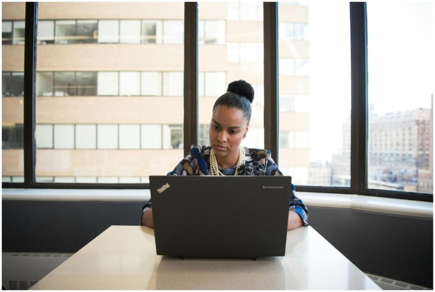 Professional woman using a laptop at a desk in a m