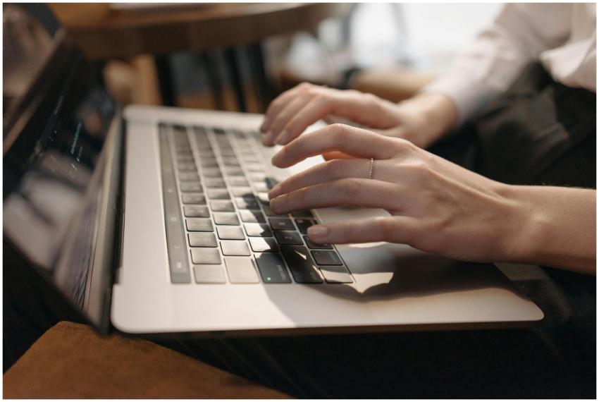 Close-up of hands typing on laptop in a cozy setti