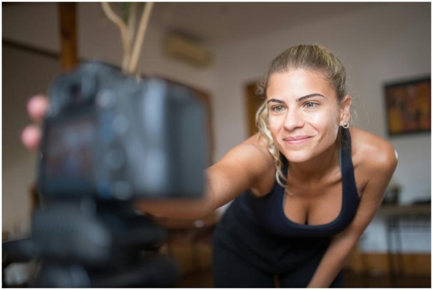 Smiling woman in sportswear setting up a camera in