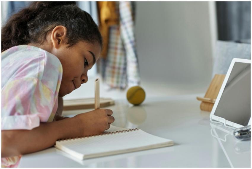 A young girl concentrating on homework at home usi