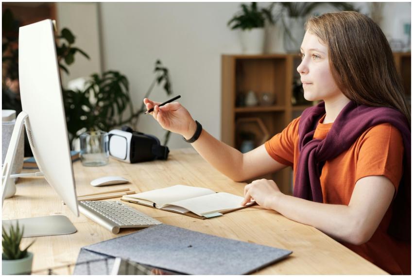 Teen girl in home office studying online using a c