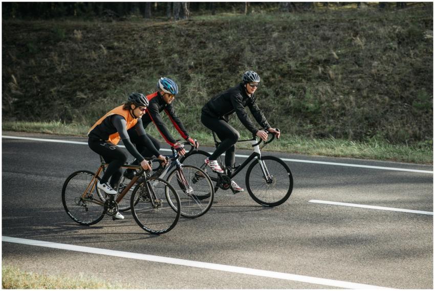 Three cyclists riding bikes on an open road, enjoy
