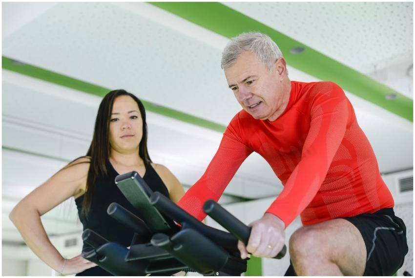 Elderly man exercising on stationary bike with tra