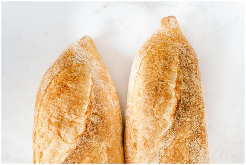 Two freshly baked baguettes on a white surface, sh