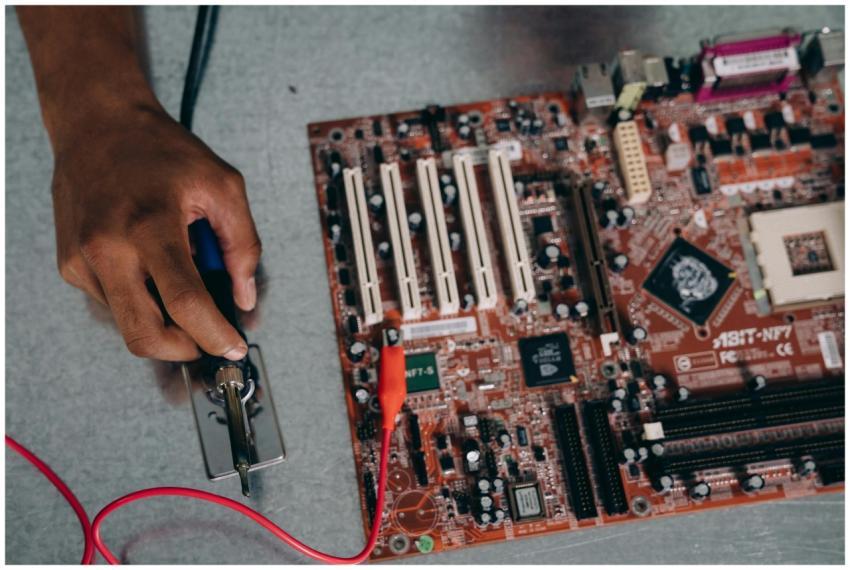 An engineer uses a soldering tool on a motherboard
