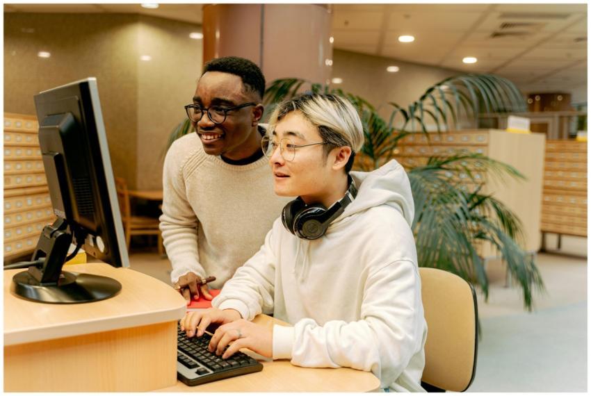 Two students collaborating on a computer in a libr