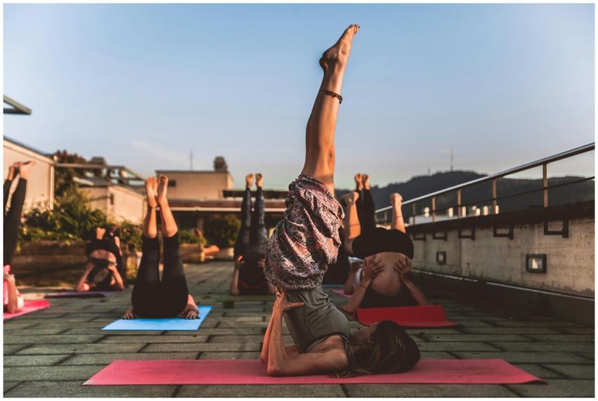 People practicing yoga on mats outdoors during sun