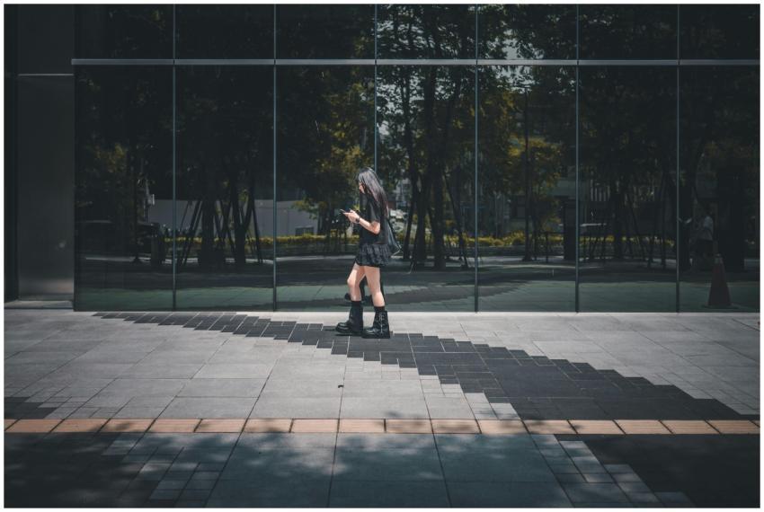 A young woman checks her phone while walking past