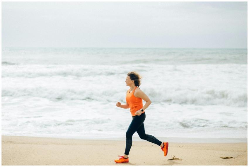 Fit woman running on the sandy beach by the ocean,