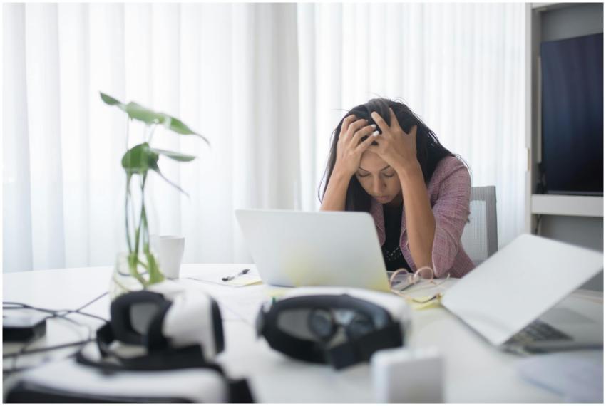 Frustrated woman sitting at desk with laptop, show