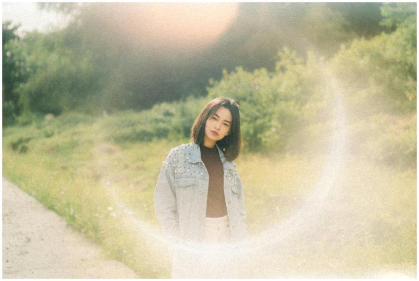 A young woman wearing a jean jacket stands in a su
