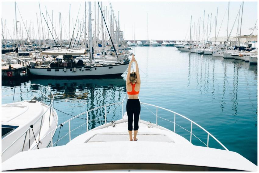 A woman stretches on a yacht deck surrounded by wa