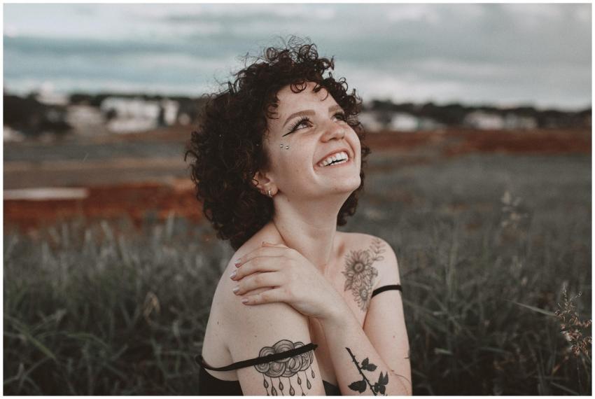 A smiling woman with tattoos enjoys the outdoors i
