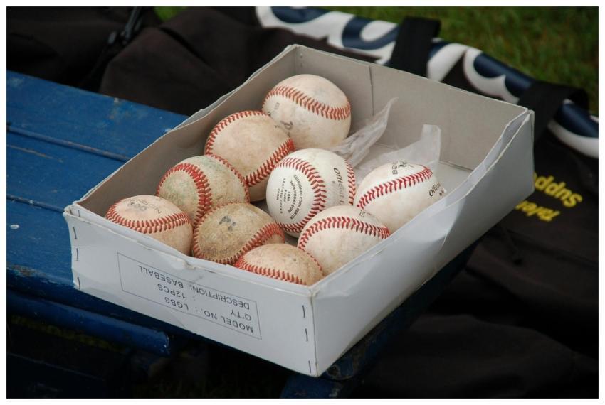 A box full of used baseballs sitting on a blue ben