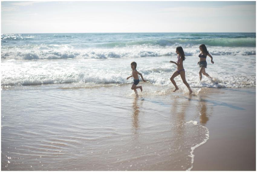 Joyful children running through waves on a sandy b