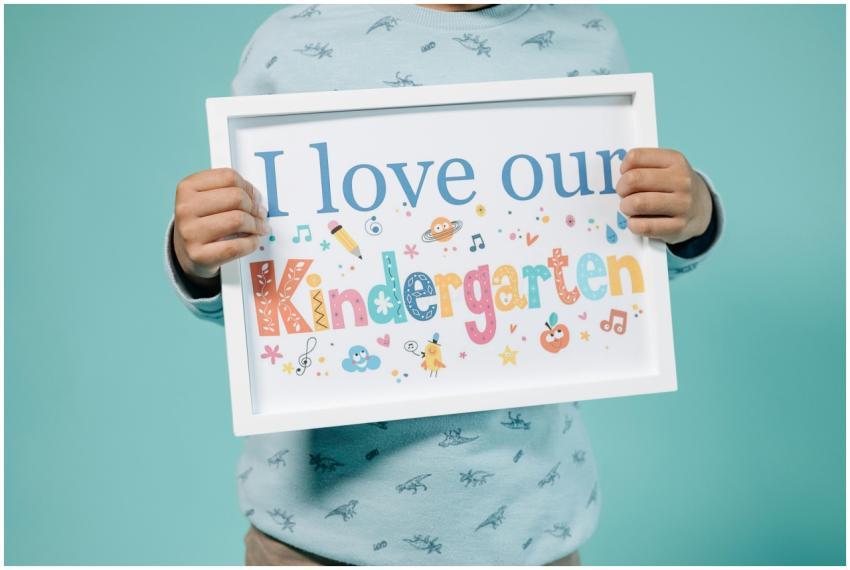 A child holding a colorful educational sign displa