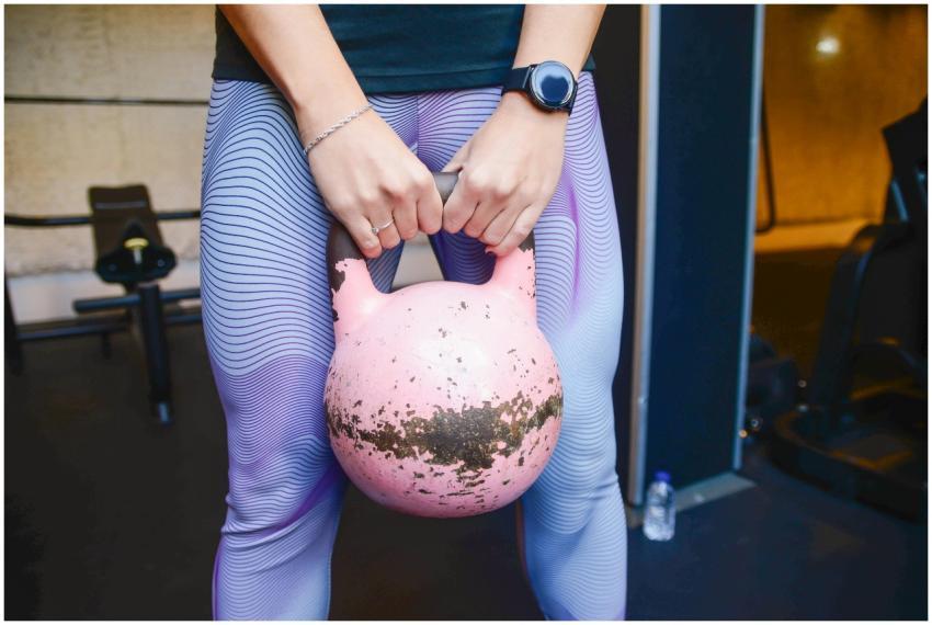 Fit woman holding a pink kettlebell during a worko
