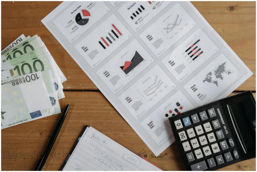 Euro banknotes, graphs, and calculator on a wooden