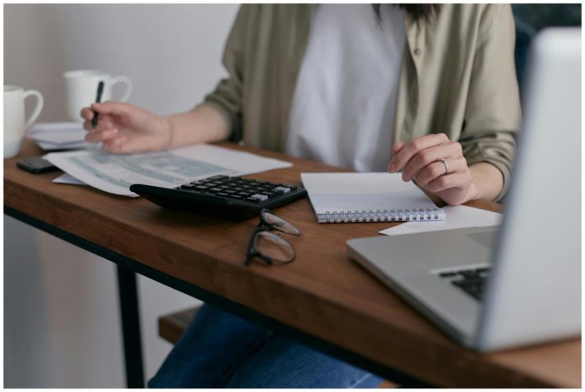 A woman manages finances at home, using a laptop a