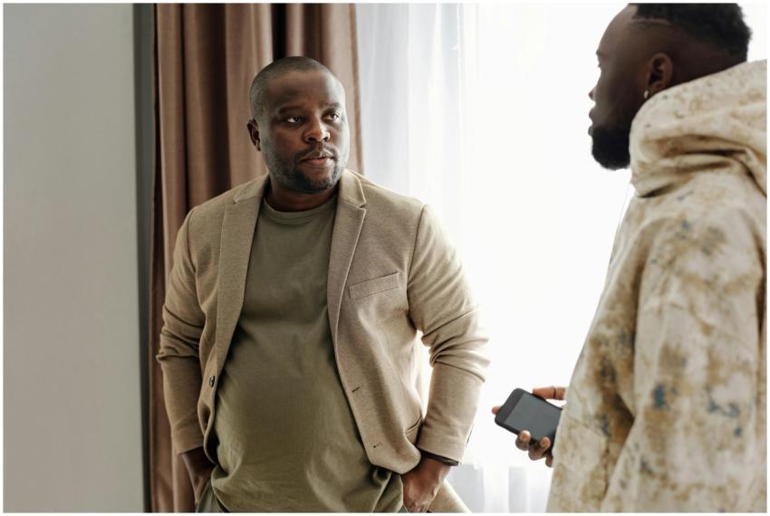 Two men engaged in a serious conversation indoors,