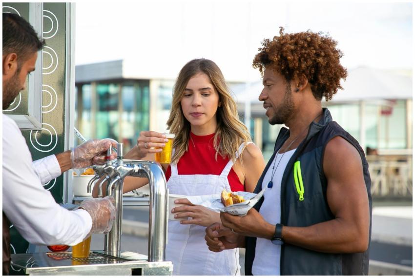 A couple enjoying beers at an outdoor food stand,