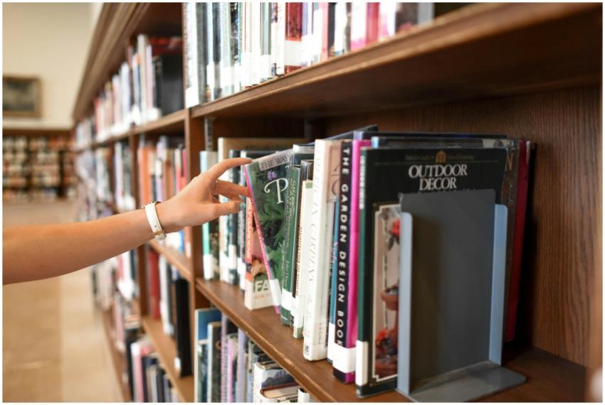 A close-up of a person's hand reaching for a book