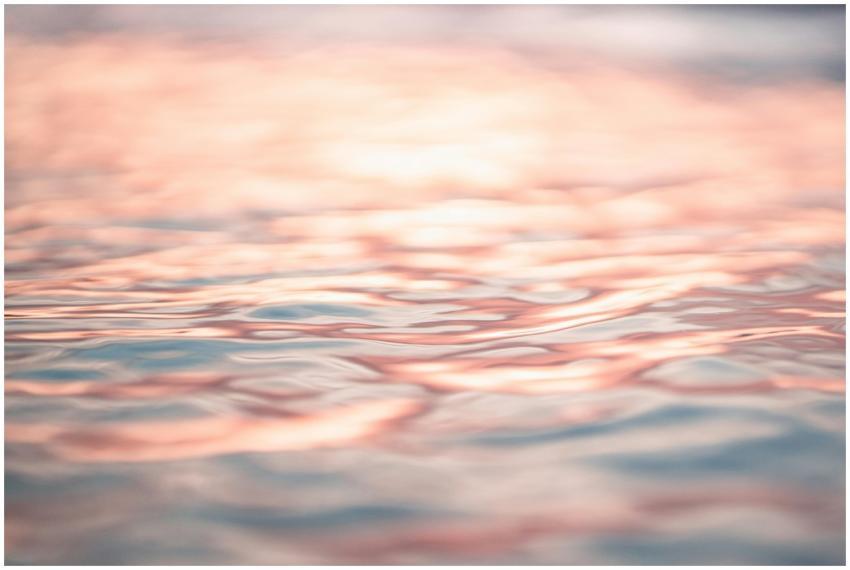 Close-up of tranquil ocean waves reflecting pink s