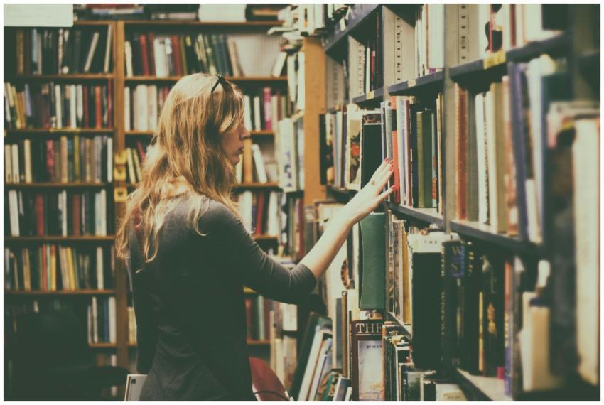 A woman explores bookshelves in a warm, inviting l