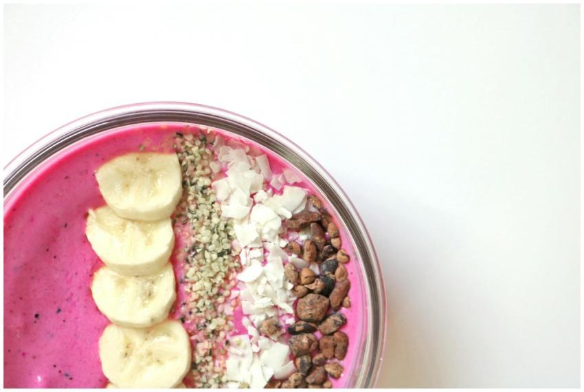Bright pink smoothie bowl with bananas, seeds, and