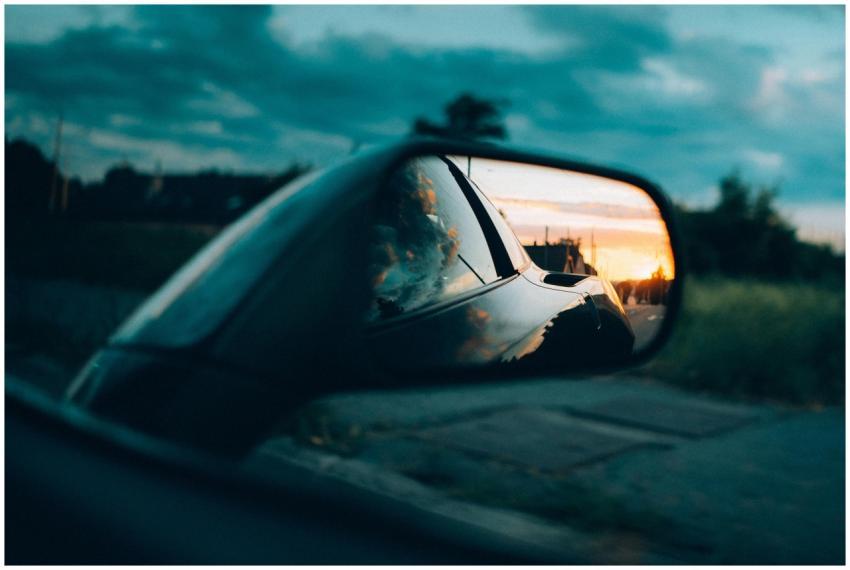 A car side mirror captures a stunning sunset with