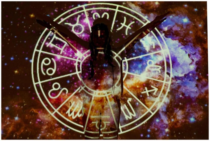 Silhouette of person extending arms against zodiac