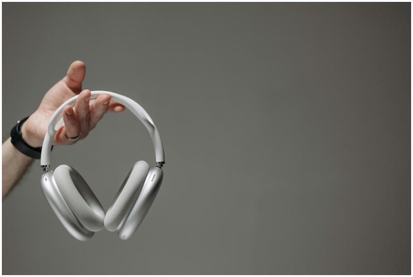White wireless headphones held by a hand against a