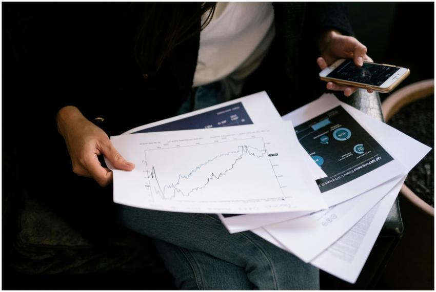 A person reviews stock market graphs on paper and