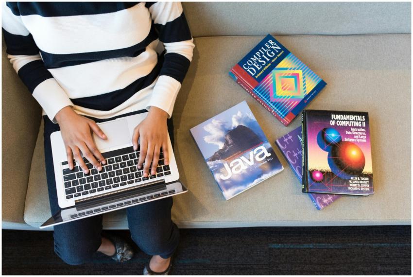 Woman using laptop on sofa, surrounded by programm