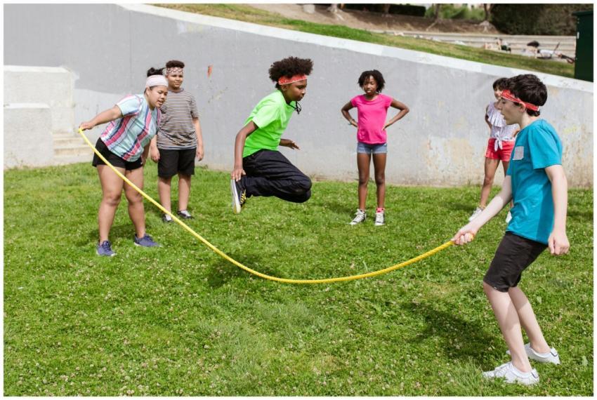 Group of children having fun jumping rope on a sun