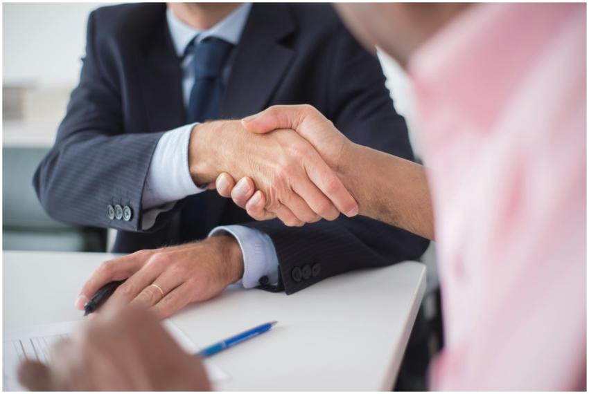 Two businessmen shaking hands across table, symbol