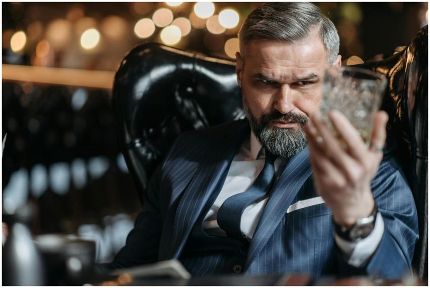 Mature businessman in a suit inspecting a glass of