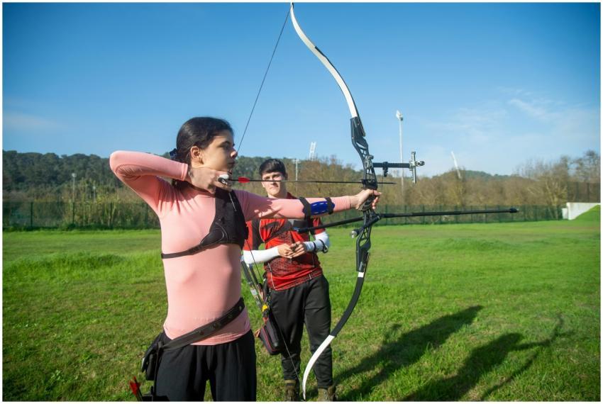 Focused woman practicing archery outdoors with rec
