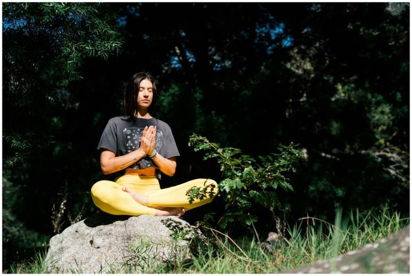 A woman practicing yoga outdoors, seated in a medi
