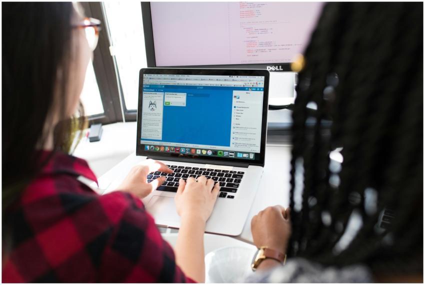 Two women working together on a laptop in a bright